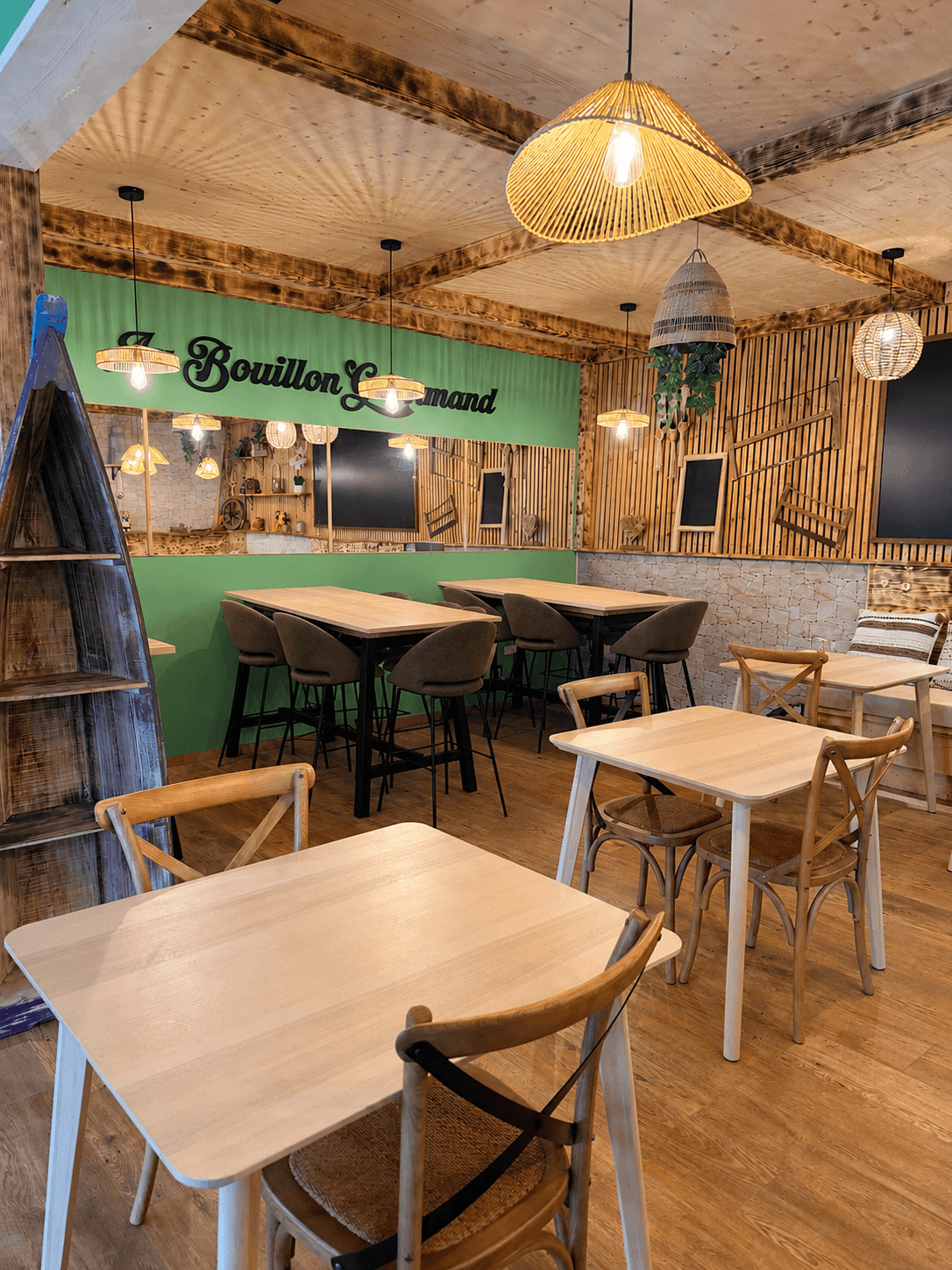 La salle du restaurant, tables en bois clair et mur vert